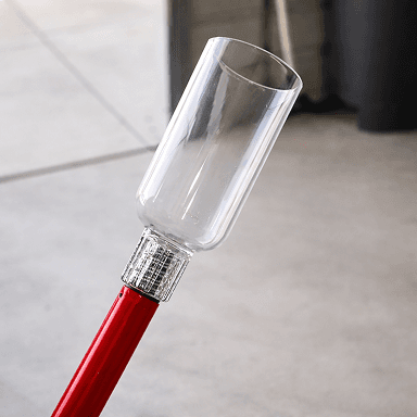 Un recolector de fruta con copa transparente en un poste rojo, usado para alcanzar las ramas altas de mora
