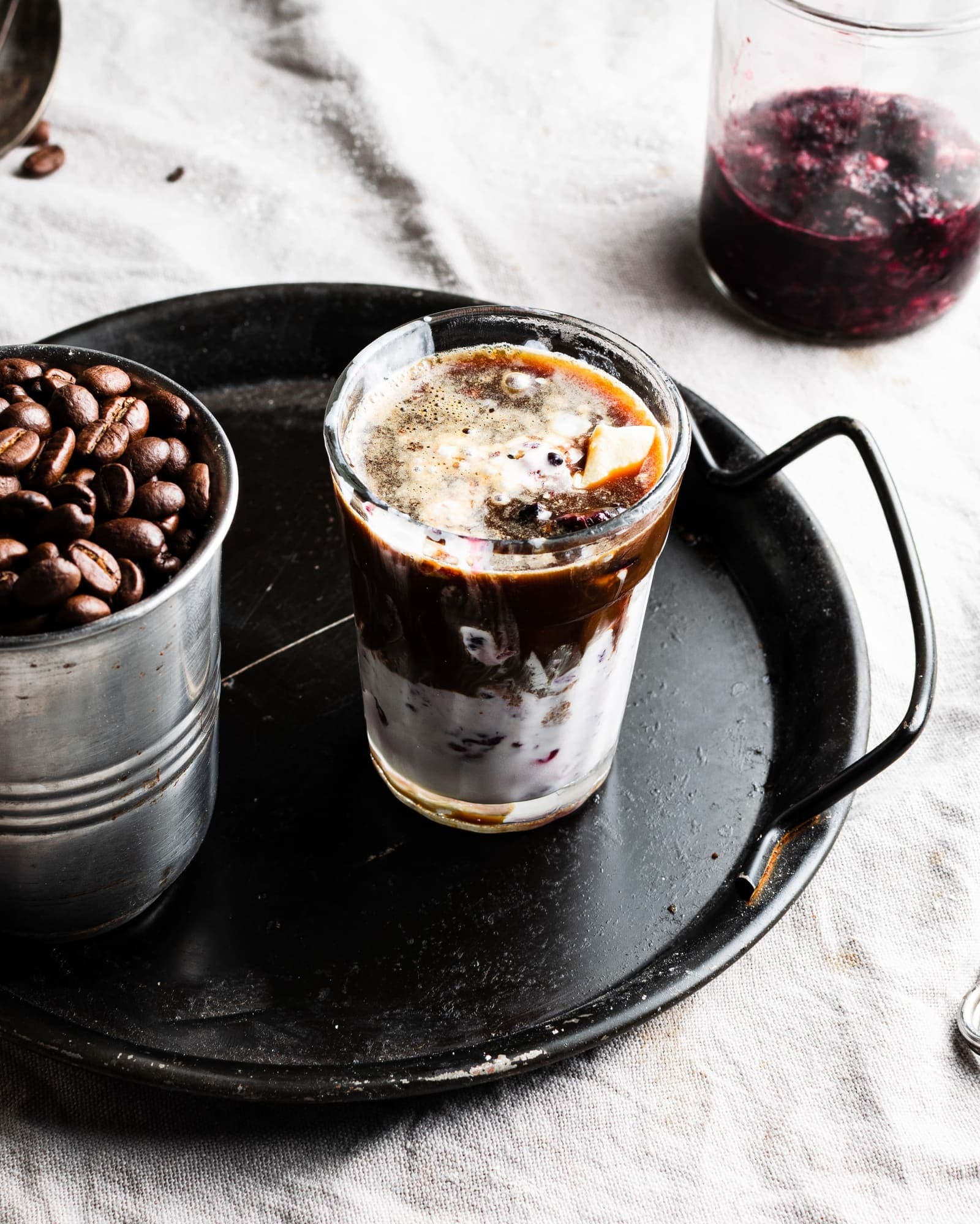 Affogato de mora en un vaso con espresso vertido sobre crema y compota de mora, junto a granos de café, Brentwood, CA