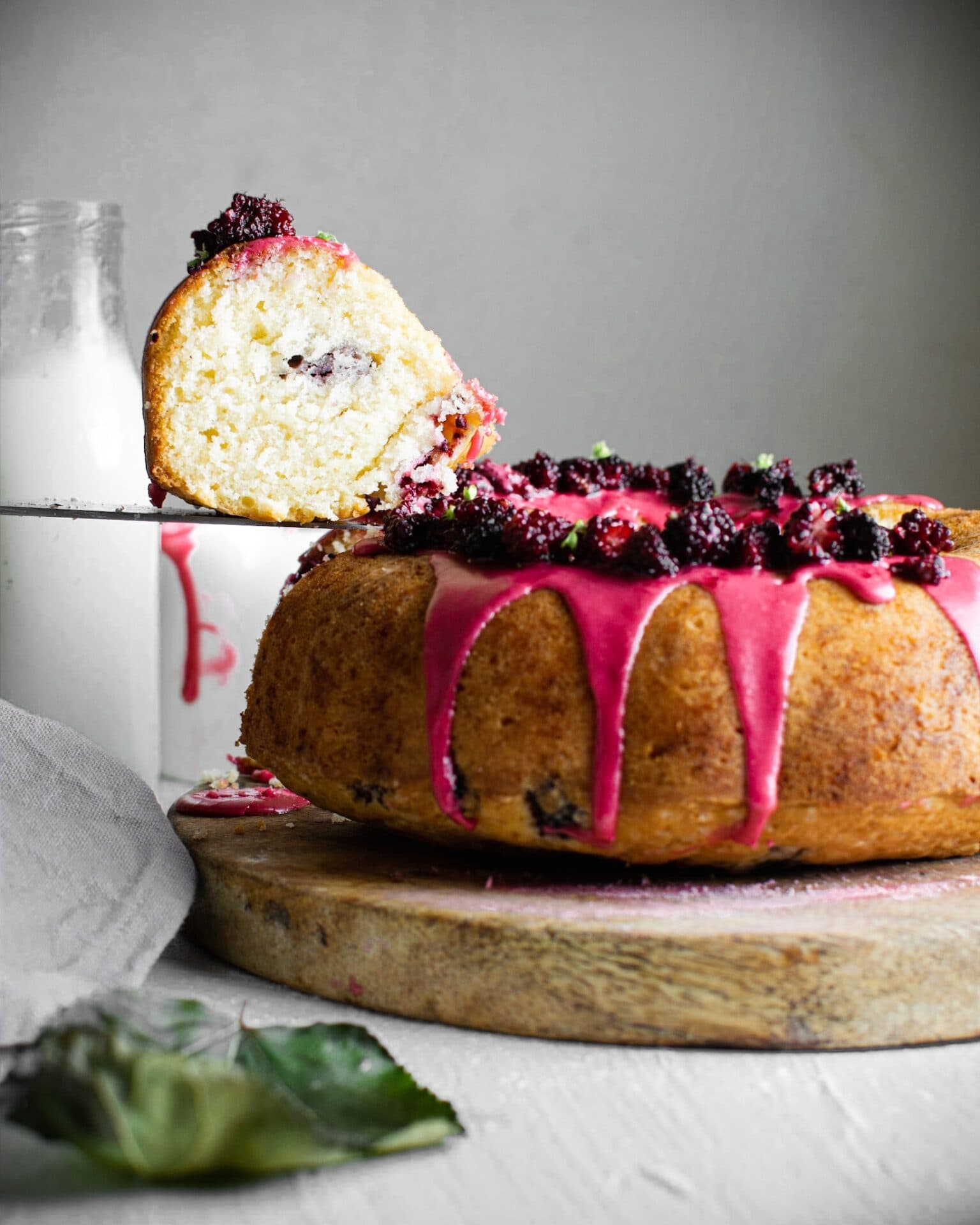 Bizcocho bundt de mora con glaseado rosa y moras frescas, una rebanada levantada con una pala para pastel, Brentwood, CA