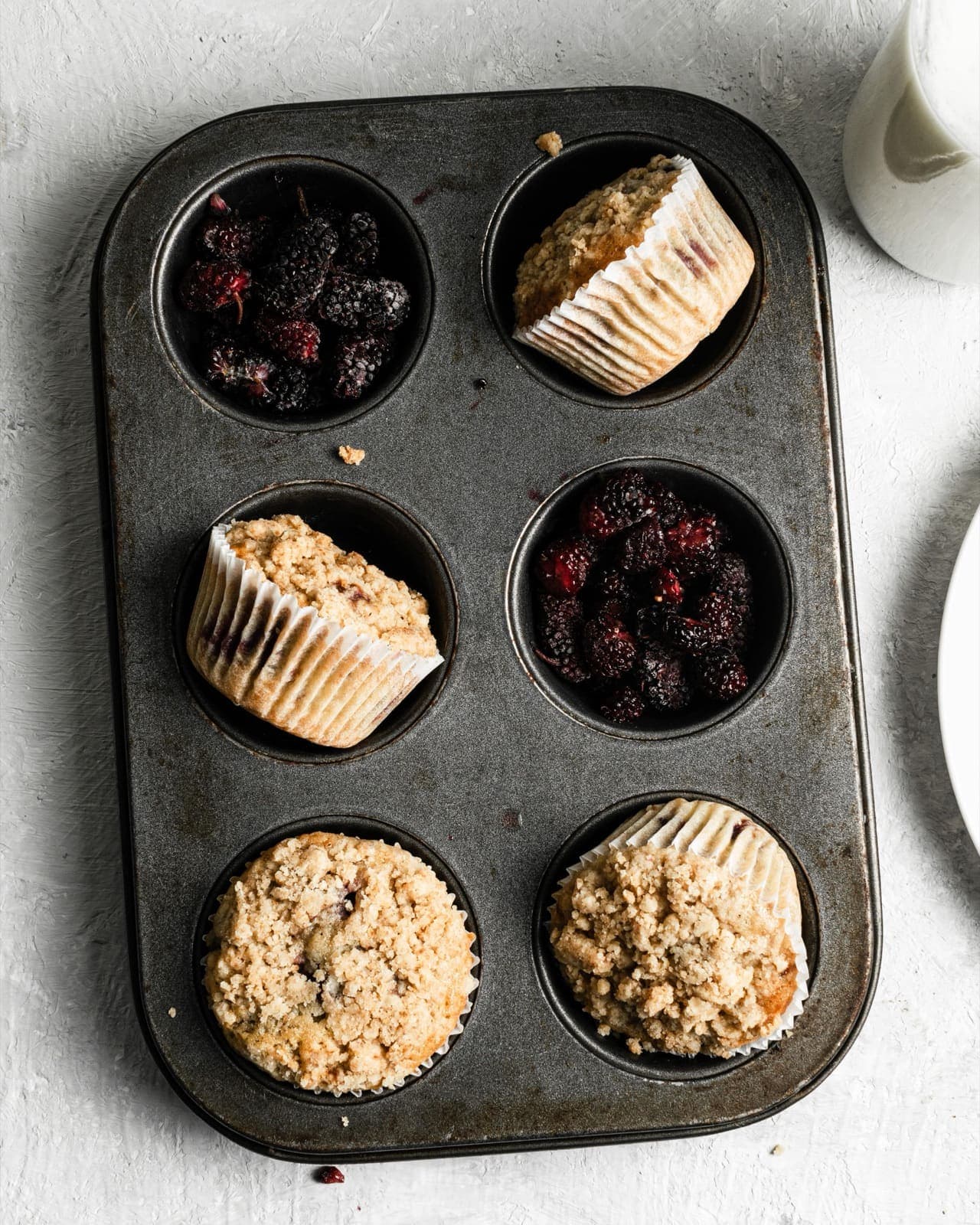 Muffins de mora con crumble junto a tazones de moras frescas, en un molde vintage para seis muffins, Brentwood, CA