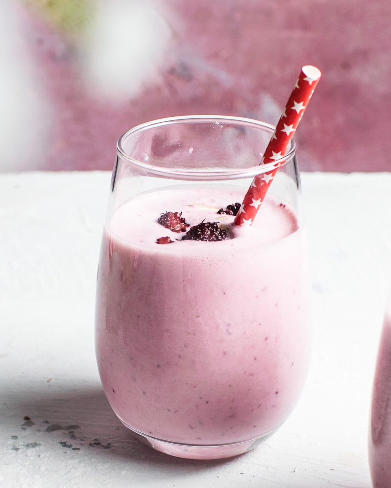 Vaso de lassi rosa de mora, coronado con moras frescas y un popote de papel con estampado de estrellas rojas, Brentwood, CA
