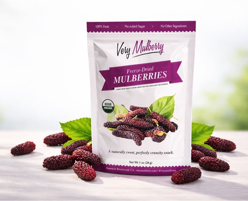 Bolsa de moras liofilizadas Very Mulberry sobre una mesa rodeada de moras frescas del Himalaya, Brentwood, CA