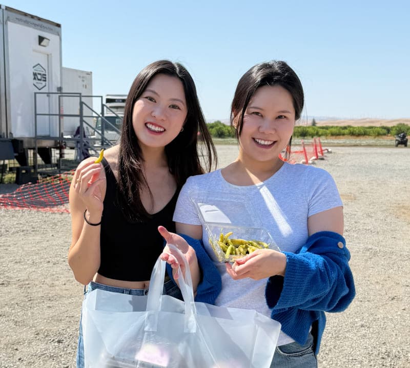 Two smiling women holding a bag and a container of golden mulberries at Very Mulberry farm, Brentwood, CA